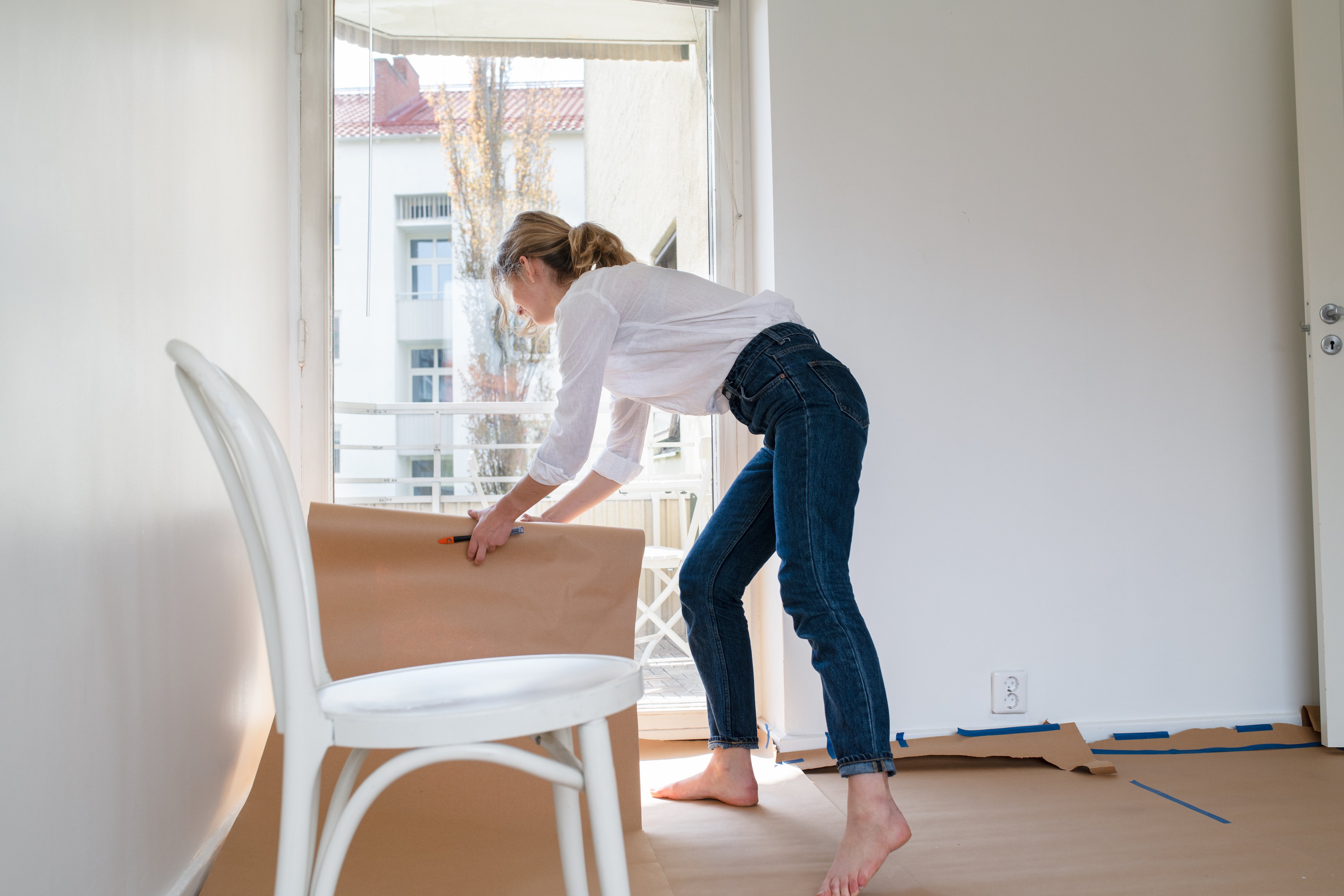 Woman covering the floors with paper to protect them from paint